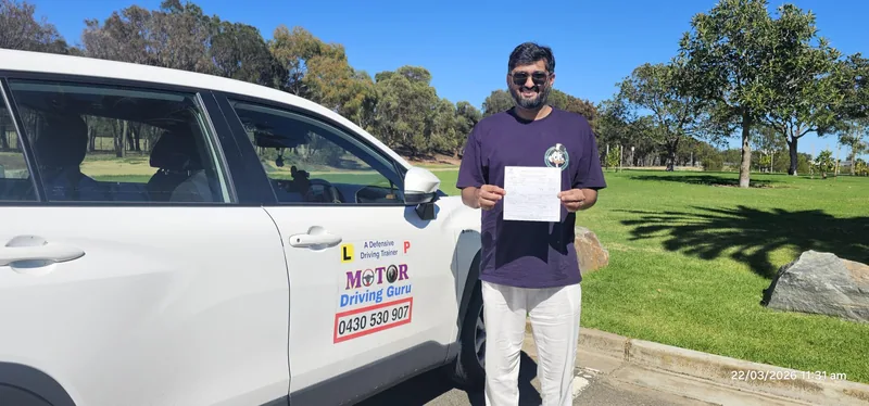 Learner in a purple shirt holding a certificate beside the school car