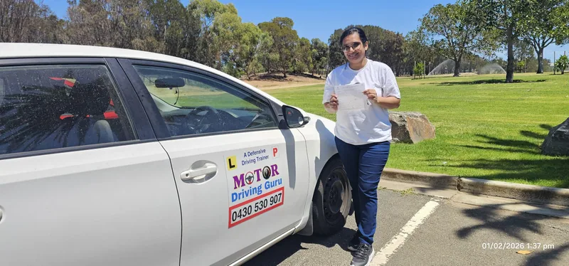 Learner holding a certificate beside the Motor Driving Guru school car